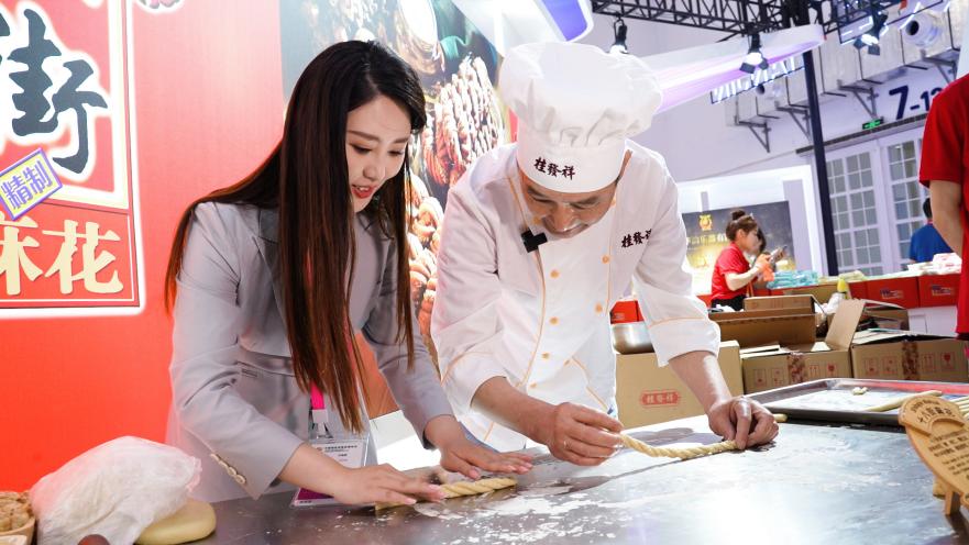 今年4月，在2023年中国国际消费品博览会现场，记者体验中华“老字号”传统美食的制作工艺。人民网记者 张力洋摄